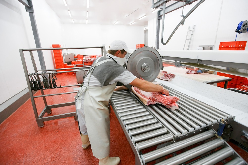 trabajador cortando carne en matadero